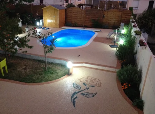 Plage de piscine en moquette de pierre avec motif rose incrusté, de nuit
