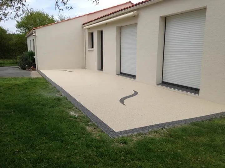 Terrasse en moquette de pierre beige avec bordure foncée après rénovation