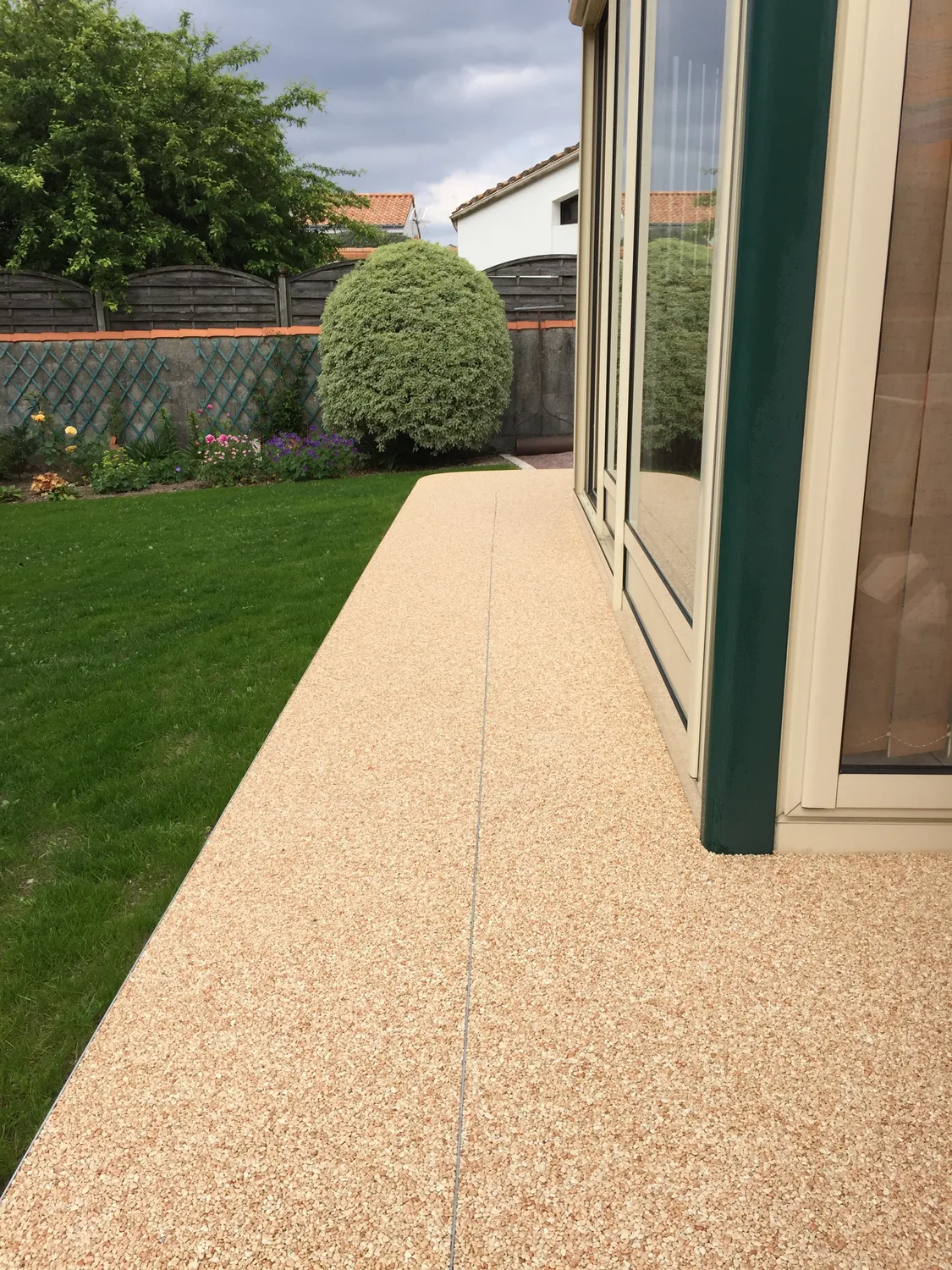 Terrasse en moquette de pierre beige le long de la maison