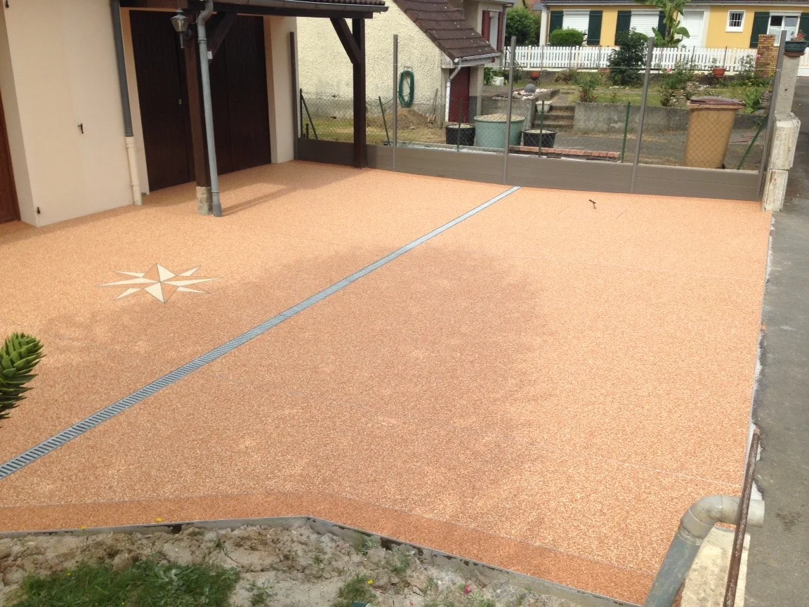 Cour en moquette de pierre saumon avec motif rose des vents